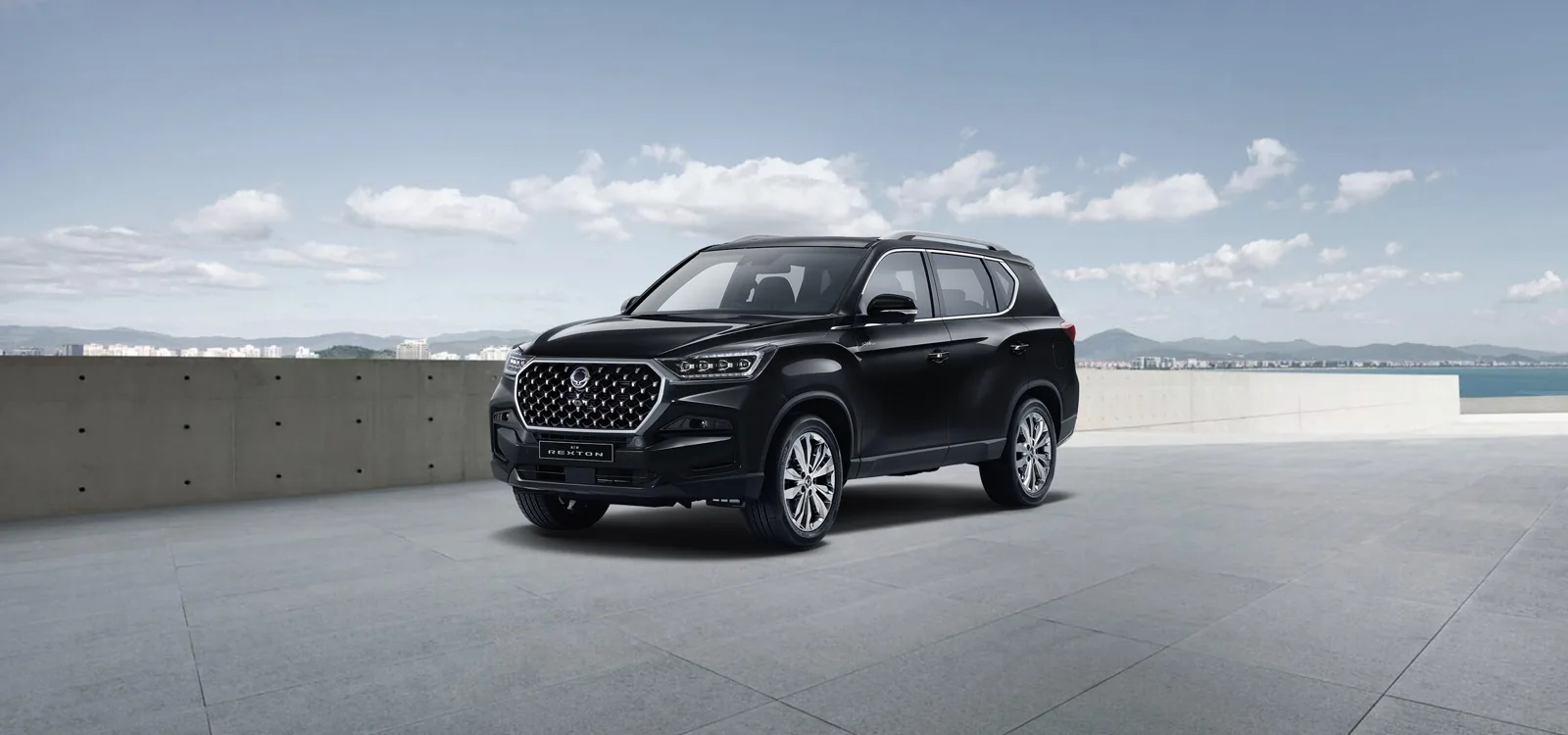 KGM Rexton 2026 in Space Black auf einer Terrasse mit Blick auf das Meer