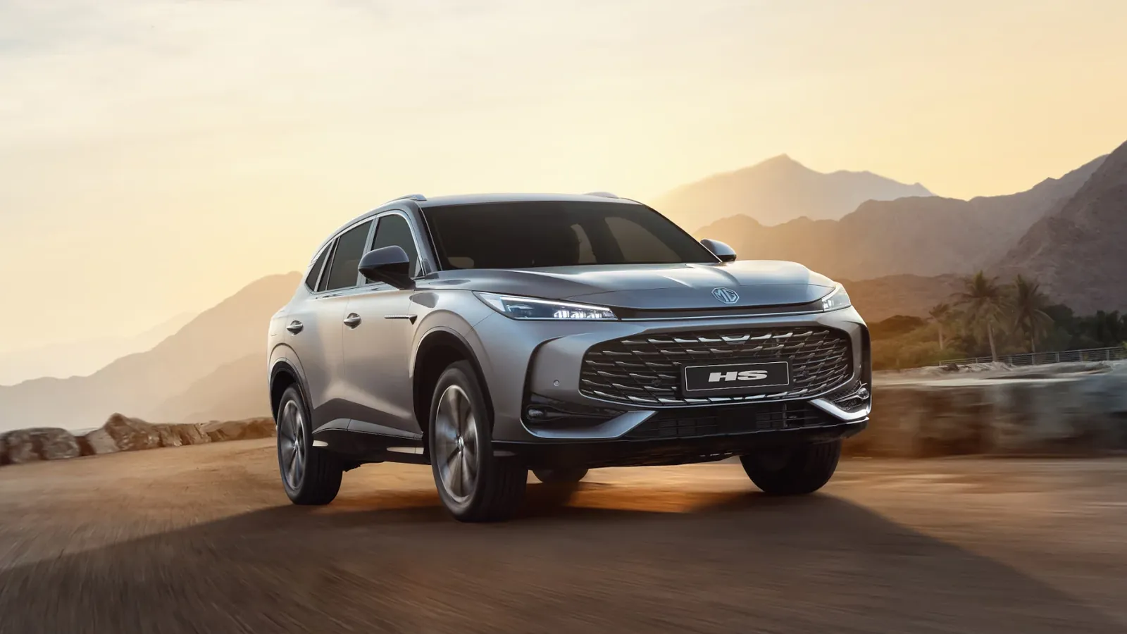 MG HS 2026 الجديدة باللون الرمادي أمام الجبال عند غروب الشمس
