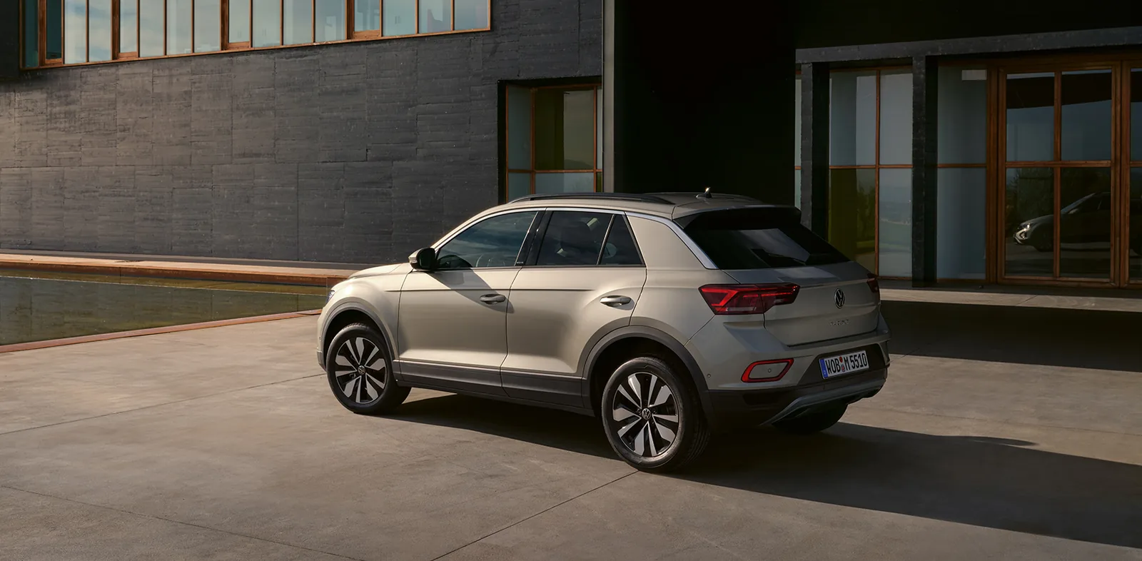 فولكس فاجن T-Roc 2026 باللون الرمادي من الخلف بزاوية ثلاثية أمام مبنى حديث